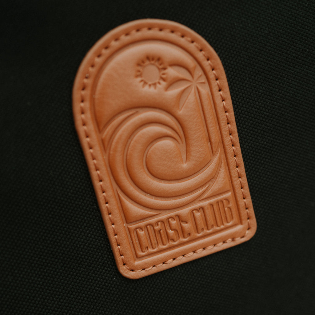Brown leather patch with a design and 'Coast Club' text on a black background