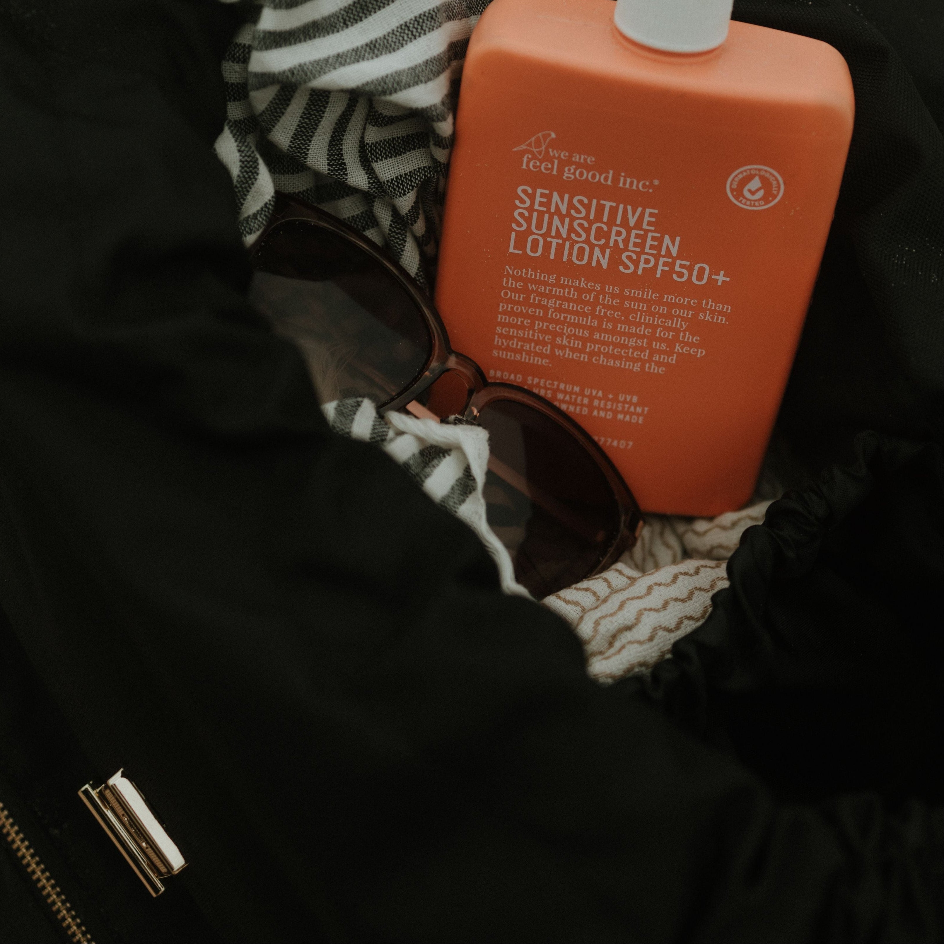 Orange bottle of sunscreen lotion with a pump in oversized black backpack