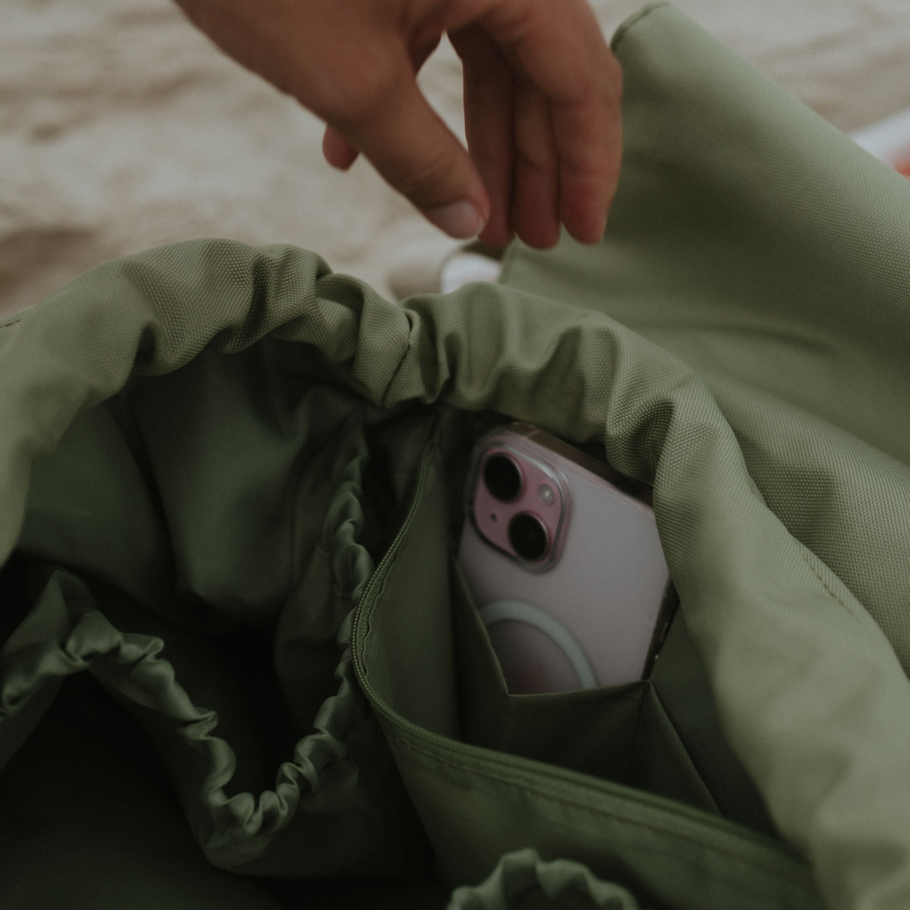 Hand reaching into a sage bag on a sandy background
