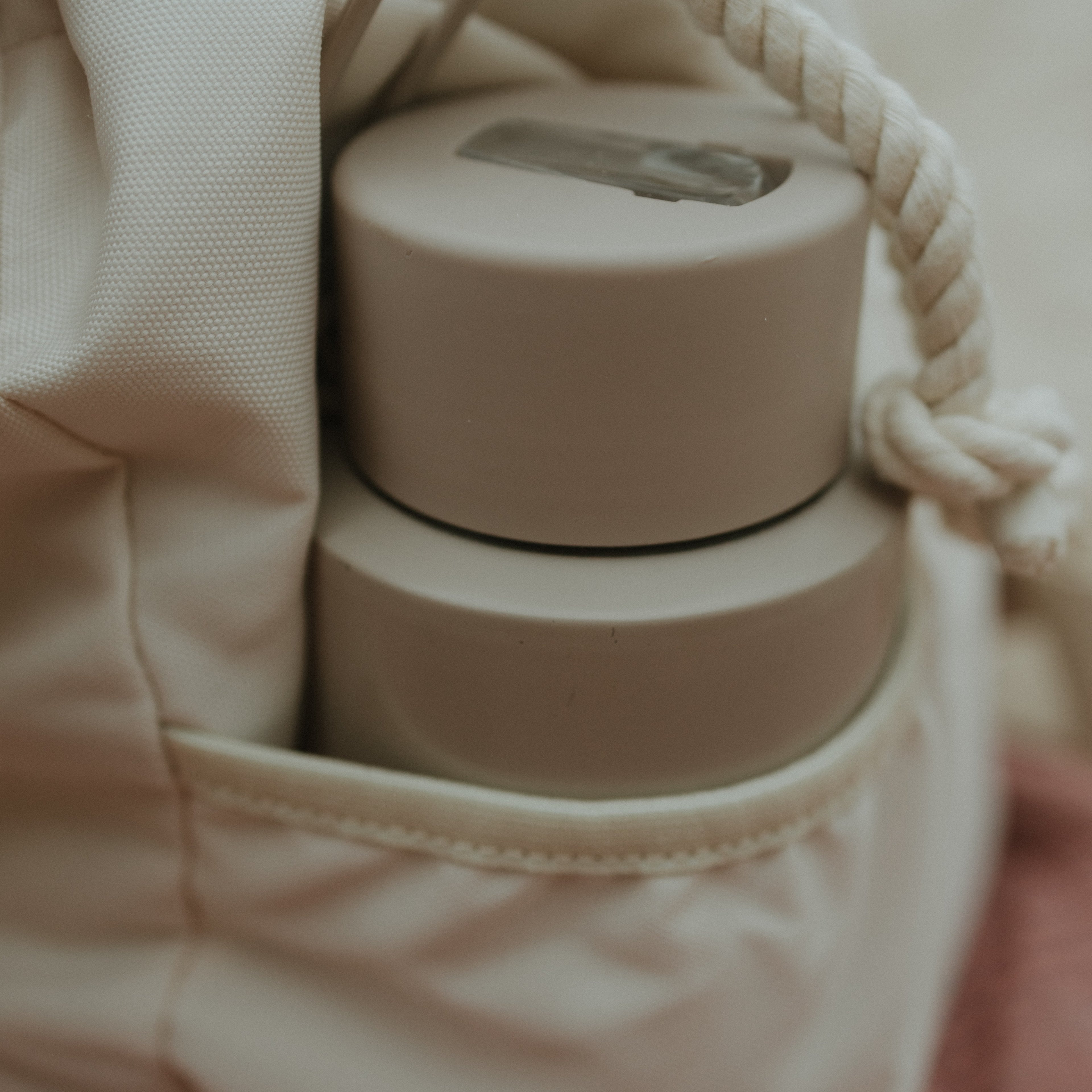 Beige drink bottle in the side pocket of the beige oversized backpack